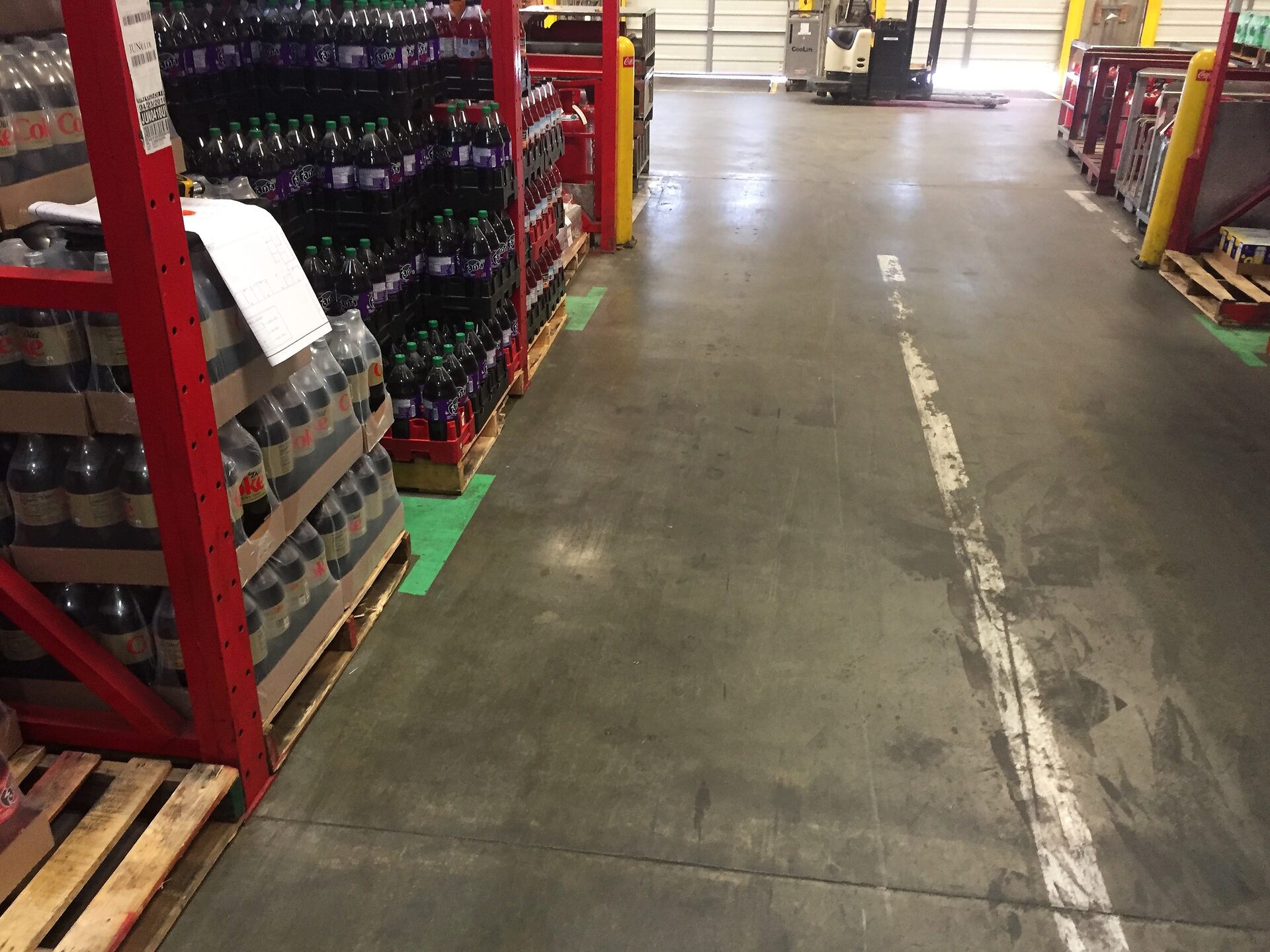 Forklift staging beverage pallets in a rack aisle