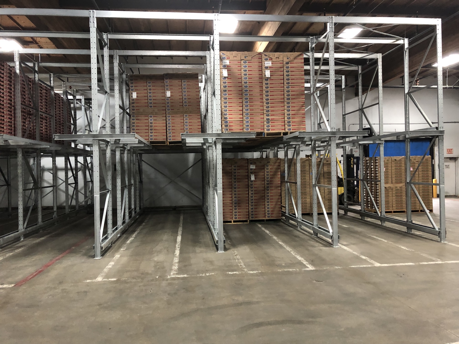 Drive-in rack loaded with stacked crates as a forklift stages product