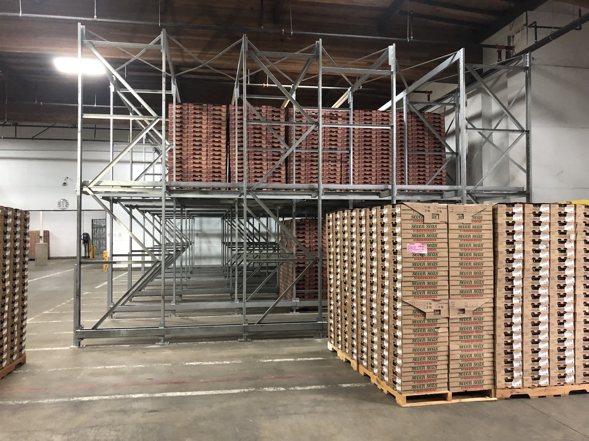 Drive-in rack mezzanine with staged cardboard case pallets below