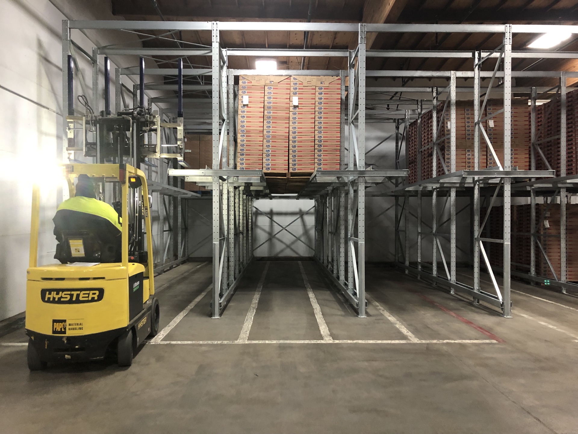 Forklift operator loading crates into a drive-in rack lane
