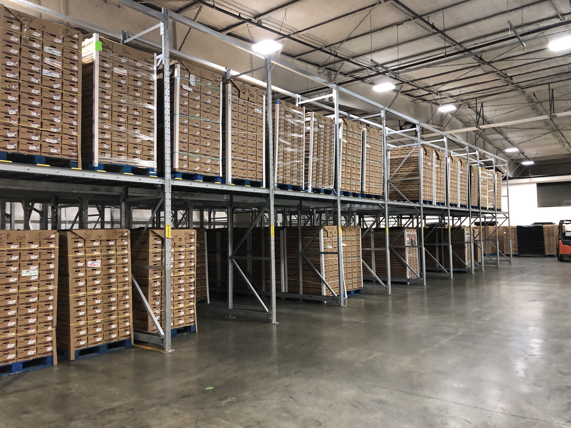 Long aisle view of pick rack shelving stocked with crates